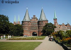 Das Holstentor in Lübeck, im Hintergrund sind die Salzspeicher zu sehen  -   Für eine größere Darstellung bitte auf das Bild klicken.